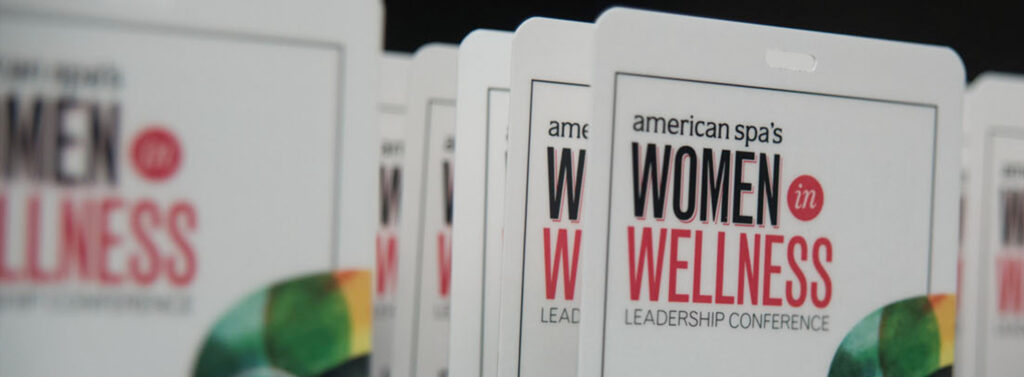 Alt-Text: "Women in Wellness badges at Gharieni spa equipment event."