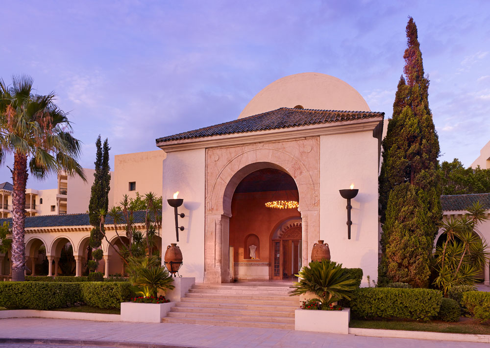 Luxury spa entrance with elegant arches, lush greenery, and ambient lighting at sunset.