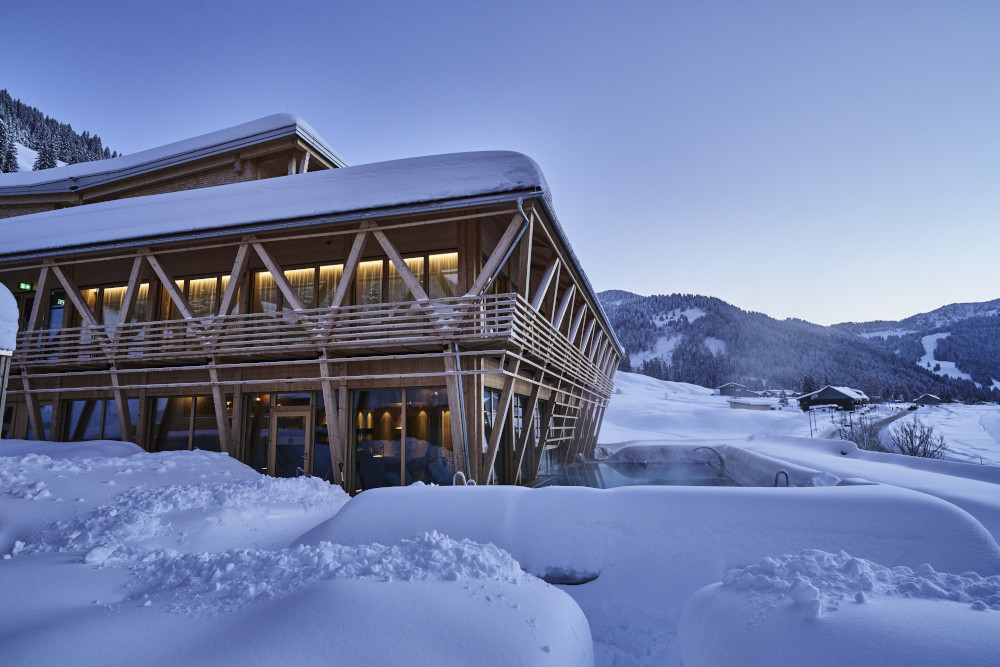 Modern spa retreat with snow-covered wooden architecture in a serene mountain setting.