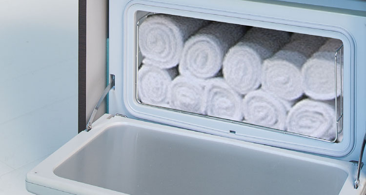 Gharieni spa towel warmer with neatly rolled white towels inside.
