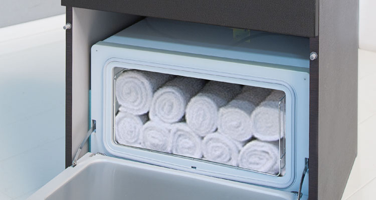 Rolled towels stored in premium Gharieni spa equipment for luxury treatments.