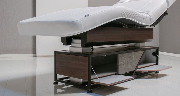 Luxurious Gharieni spa treatment table with sleek wooden base and ergonomic design.