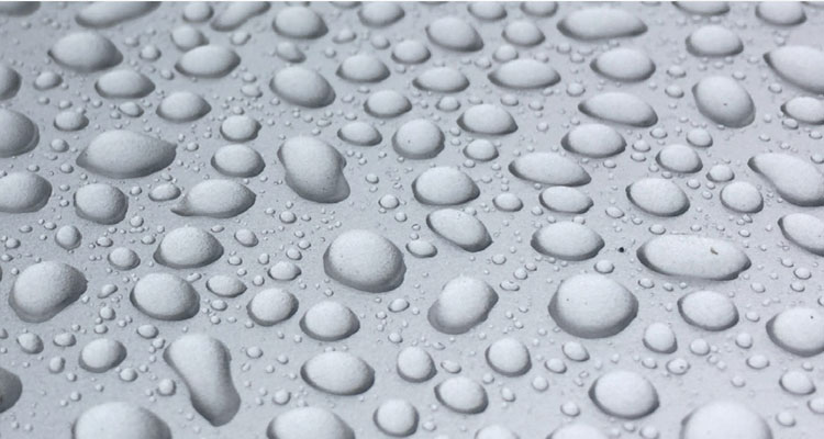 Raindrops on sleek metallic surface, highlighting premium spa equipment quality.