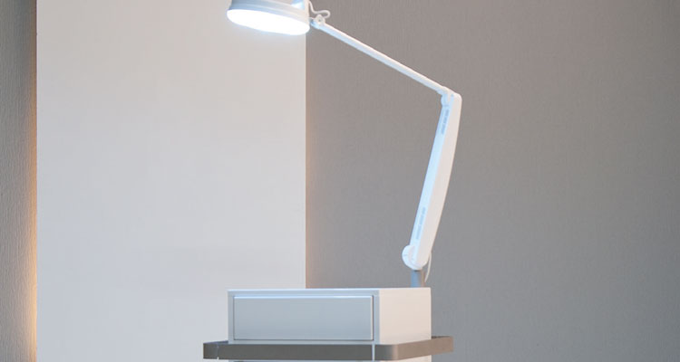 Modern spa lamp on sleek treatment table in minimalist setting.