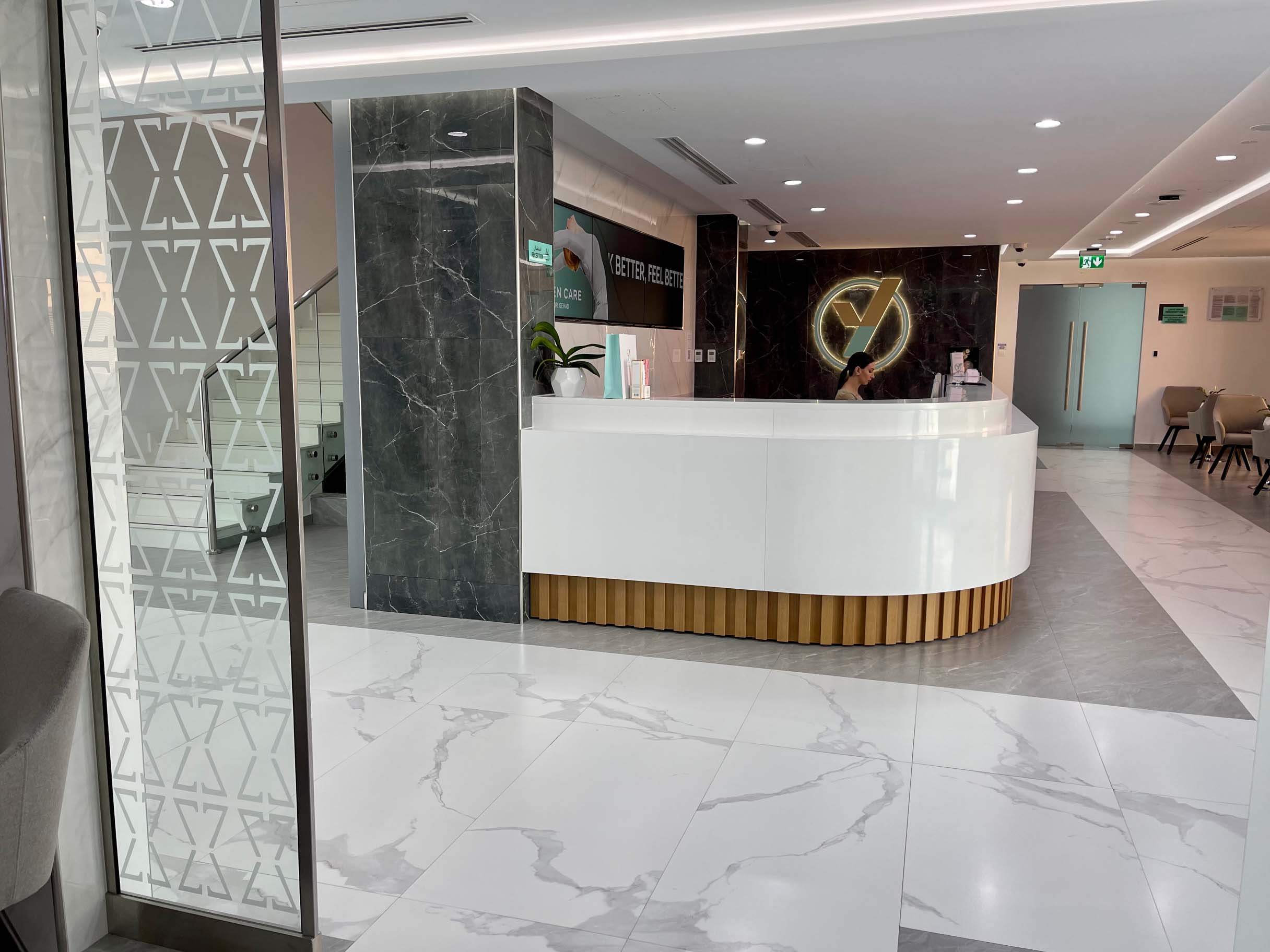 Modern spa reception with sleek white counter, marble accents, and elegant lighting.
