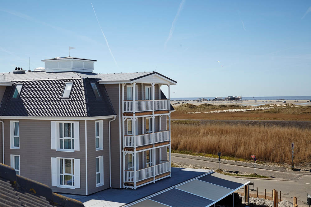 Coastal hotel with balconies, ocean view, clear sky; luxury spa setting.