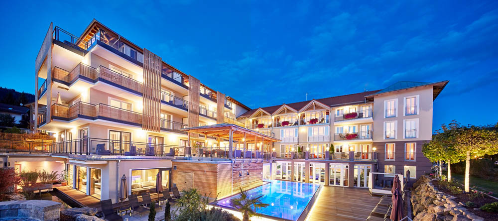 Luxurious spa resort exterior with illuminated pool at dusk, showcasing Gharieni's premium treatment tables.