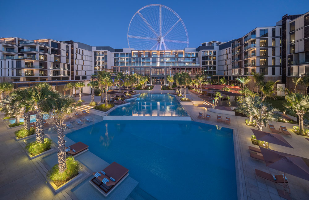 Luxurious resort pool and Ferris wheel at dusk, showcasing Gharieni spa elegance.