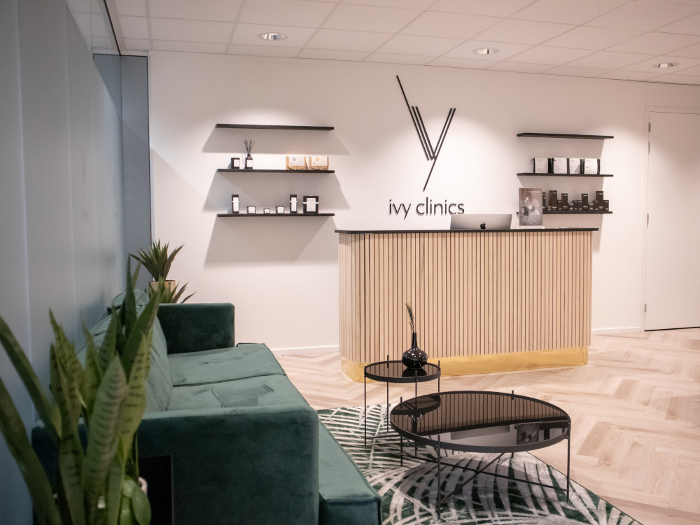 Luxurious spa reception with green sofa, modern decor, and premium treatment products.