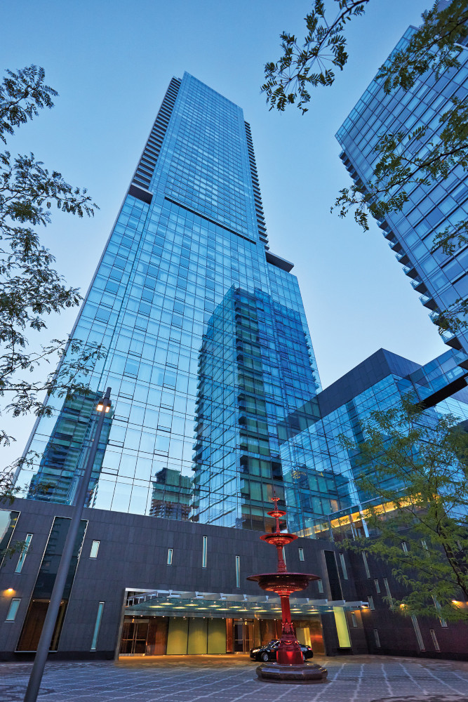 Skyscraper with modern glass facade and red sculpture, evening sky.