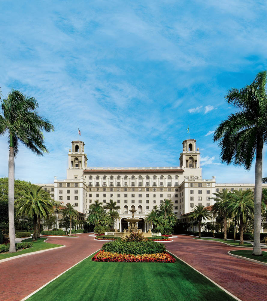 Luxurious hotel exterior with palm trees and blue sky, ideal for spa retreats.