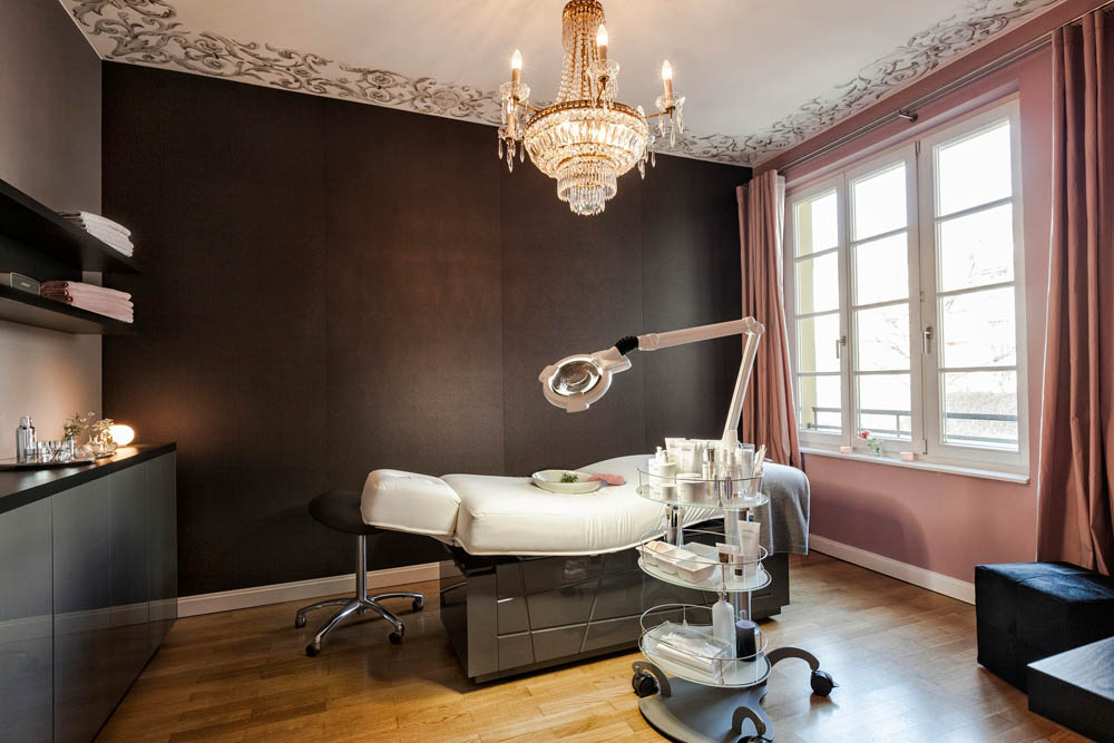 Luxurious spa room with Gharieni treatment table, elegant chandelier, and modern equipment.