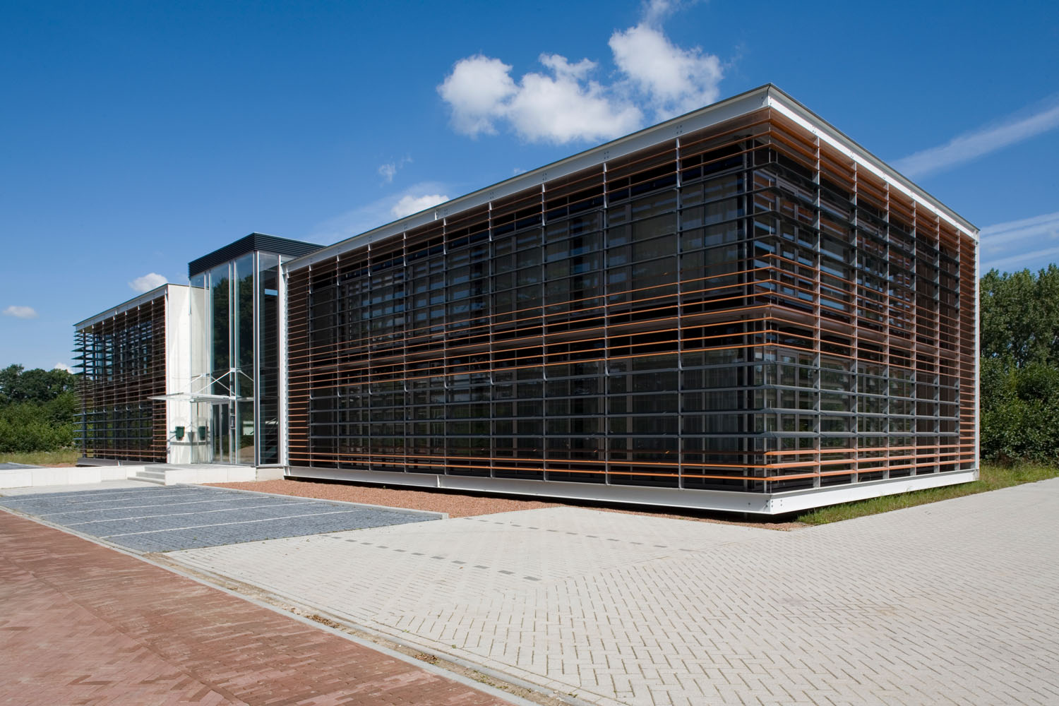 Modern office building with glass facade and wooden accents under a clear blue sky.