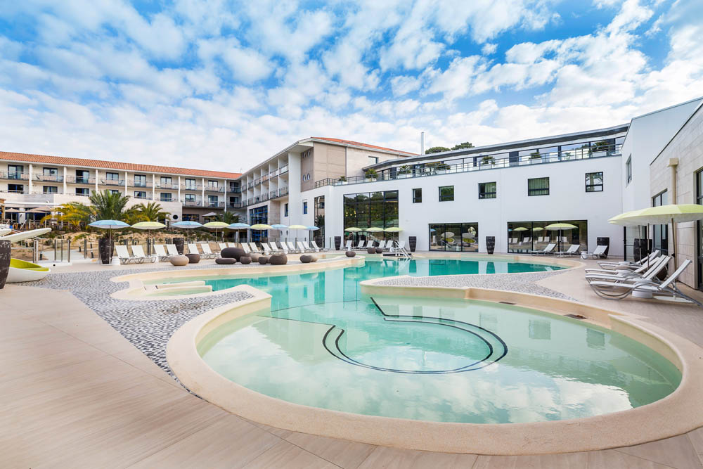 Luxurious spa poolside with premium Gharieni treatment tables under a clear sky.