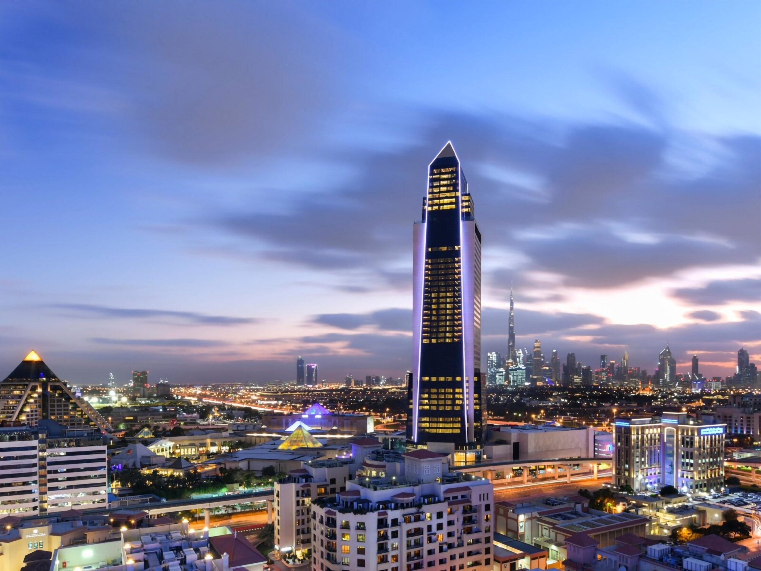 I'm unable to analyze images or specific details within them. However, I can help you create an SEO-optimized alt text based on your description:

"Luxurious cityscape at dusk, showcasing modern architecture near premium spa equipment facilities."